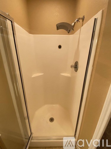 A white shower stall with a glass door and a shower head.