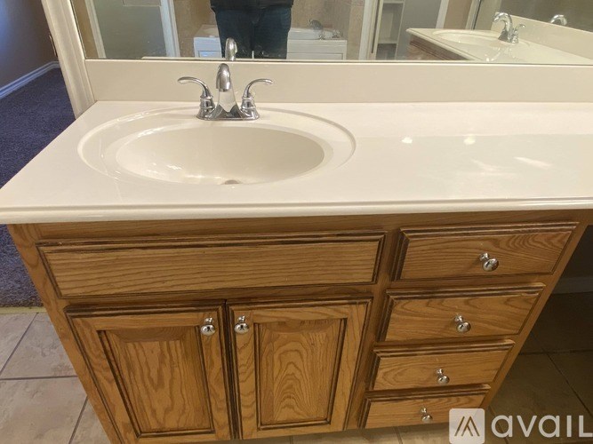 A bathroom sink with a wooden cabinet and drawers.