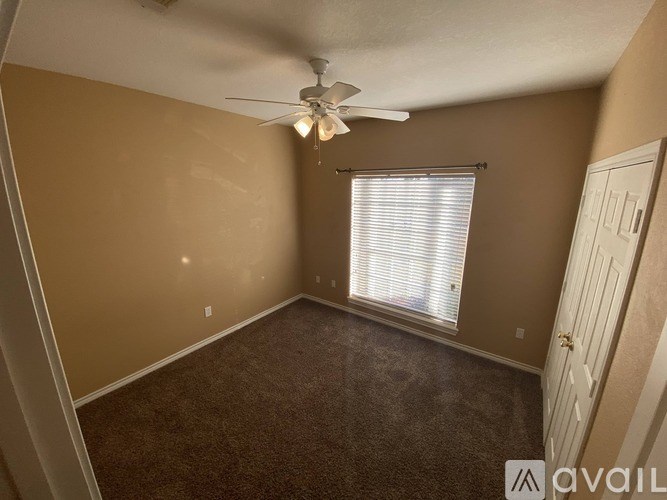 A room with a carpeted floor, a ceiling fan, and a window with blinds.
