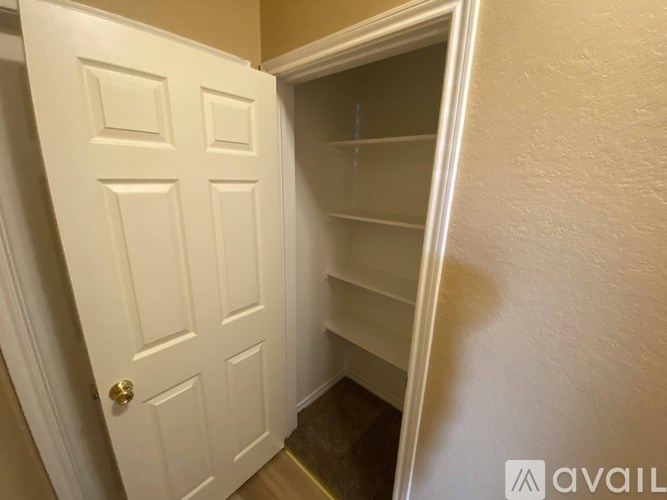 A white door with a gold handle is open to a small, empty room.