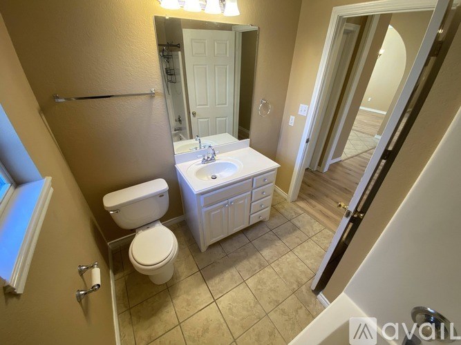A bathroom with a toilet, sink, and mirror.
