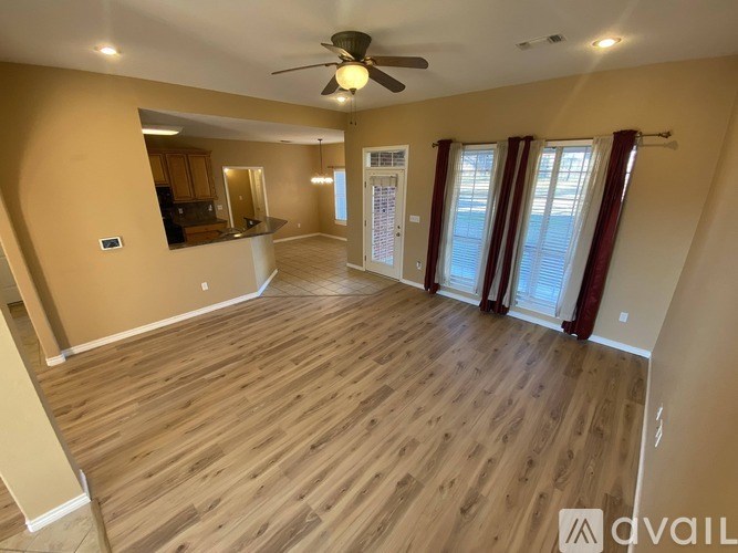 A spacious room with wooden flooring and a ceiling fan.