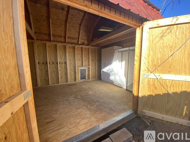 A wooden structure with a doorway open to a room with a window.