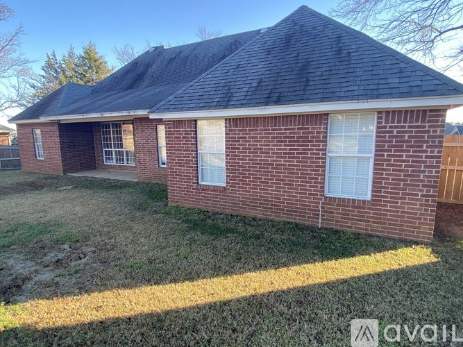 A red brick house with a black roof and a white window.