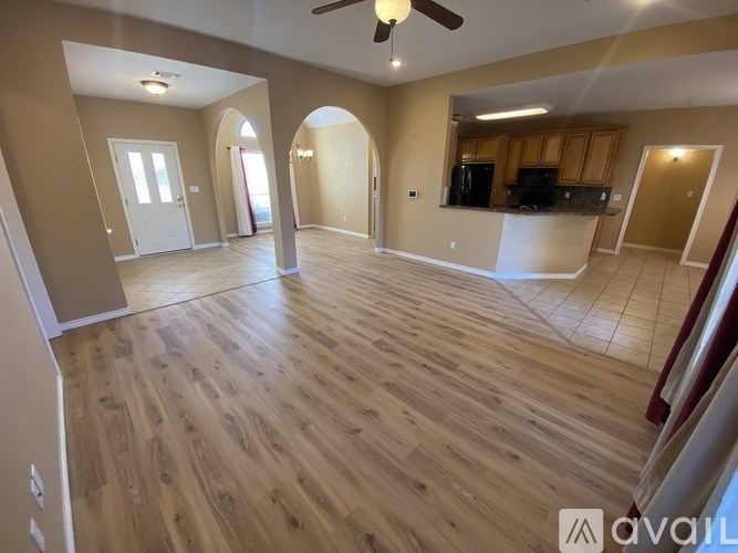A spacious living room with wooden flooring and arched doorways.