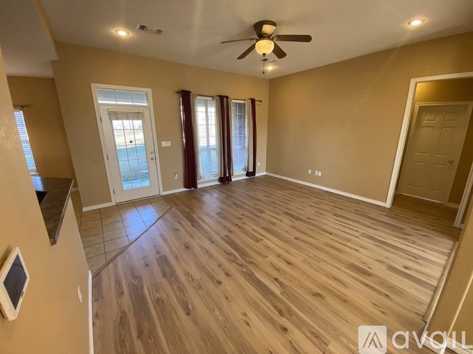 A spacious room with wooden flooring and a ceiling fan.