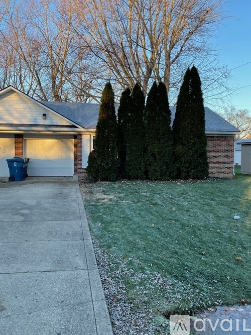 A house with a driveway and a tree in front.