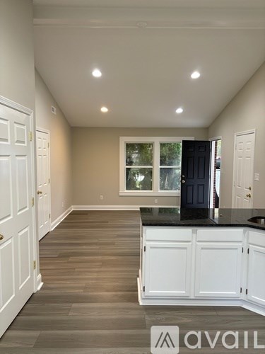 A kitchen with white cabinets and a black countertop.
