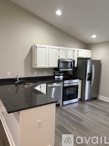 A kitchen with a black countertop and stainless steel appliances.