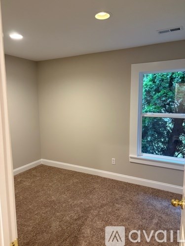 A room with a window and a carpeted floor.