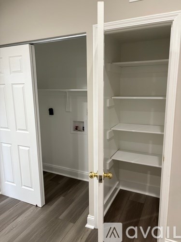 A white door is open to reveal a white pantry with shelves.