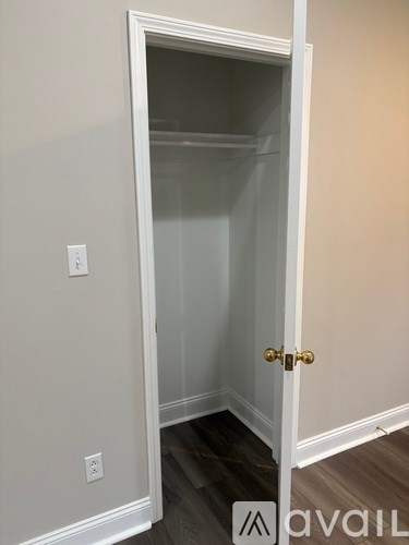 A white door is open to a room with a wooden floor.