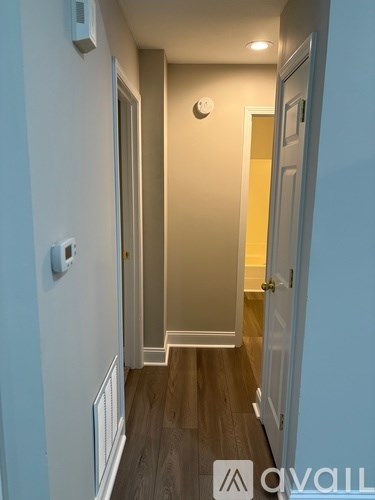 A hallway with a wooden floor and white walls.