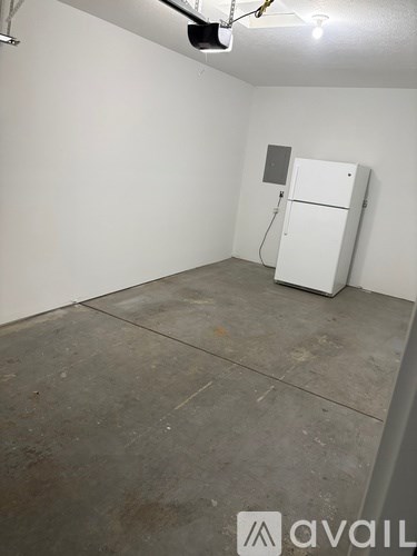 A white refrigerator in a room with a concrete floor.