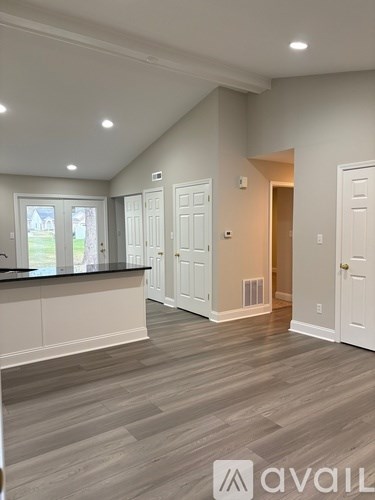 A spacious room with a kitchen area and a view of the backyard through the window.