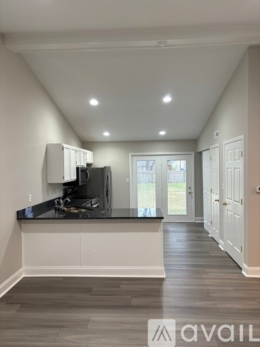 A modern kitchen with a black countertop and wooden flooring.