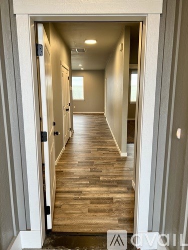 A long hallway with wood floors and white walls.