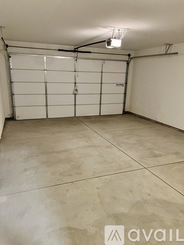 A large, empty garage with a closed white door and a tiled floor.