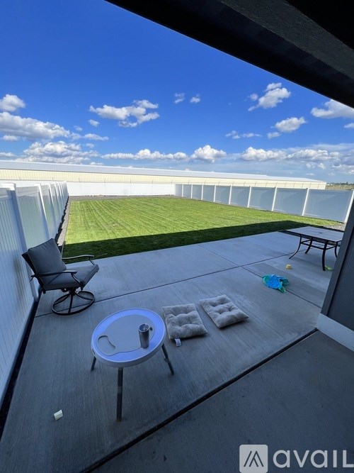 A balcony with a table and chairs overlooking a green field.