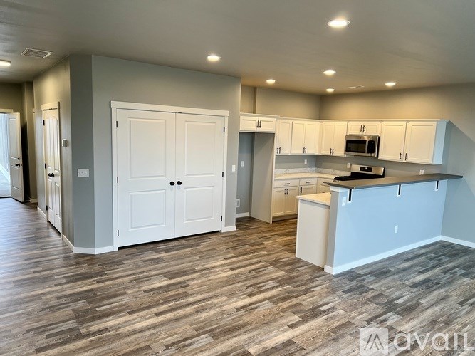 A kitchen with white cabinets and a wooden floor.