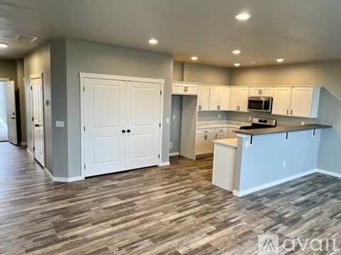 A kitchen with white cabinets and a wooden floor.