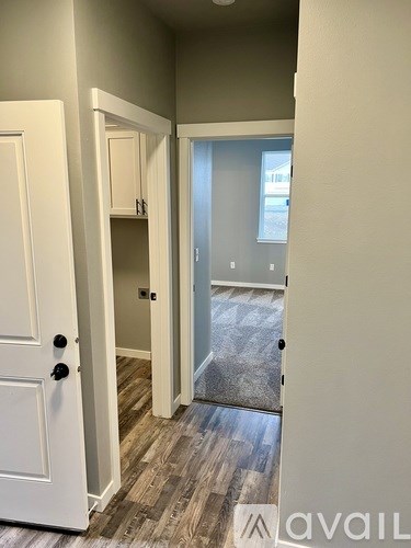 A hallway with a white door and a wooden floor.