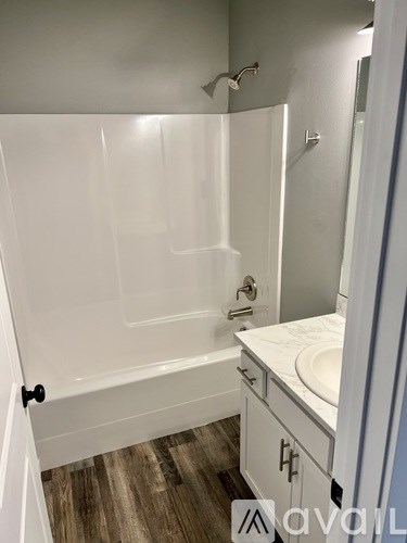 A white bathroom with a wooden floor and a white tub.