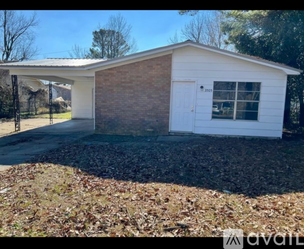 A small white house with a brick wall and a white door is for sale.