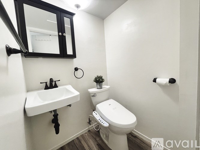 A small white toilet is in a bathroom with a white sink and a mirror.