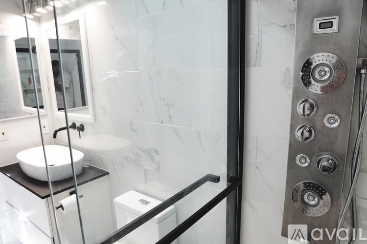 A modern bathroom with a marble wall and a glass shower stall.