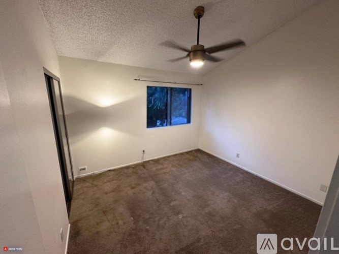 A room with a ceiling fan and a window.