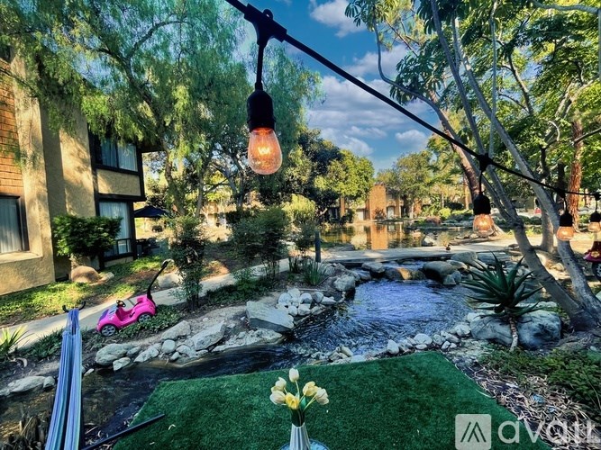 A small pond in a backyard with a pink scooter and a hanging light.
