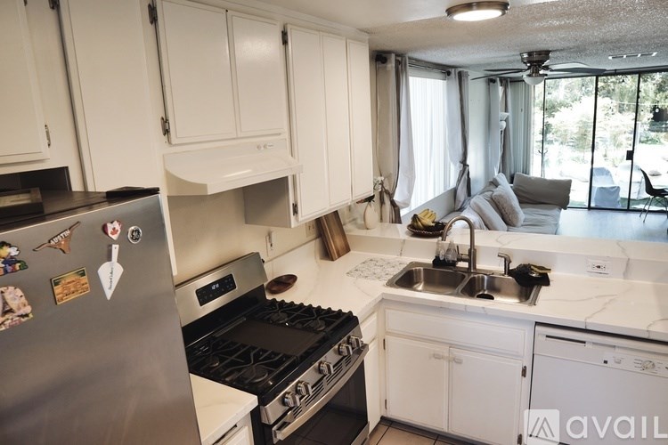 A kitchen with white cabinets and a stainless steel refrigerator.