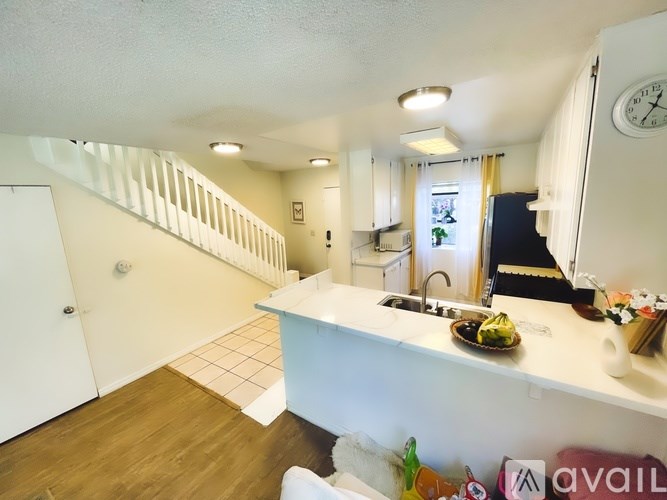 A kitchen with a white countertop and a clock on the wall.