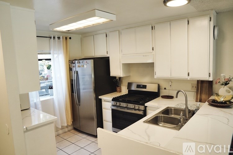 A kitchen with white cabinets and black appliances.
