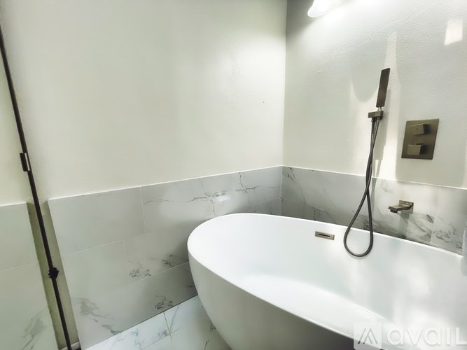 A white bathtub with a shower head attached to the wall.