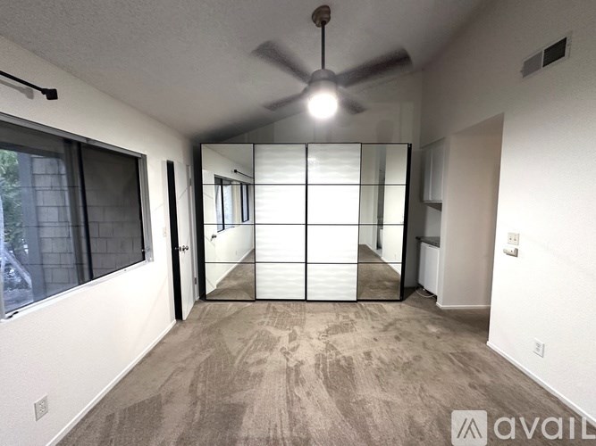 A room with a fan and a window with blinds.