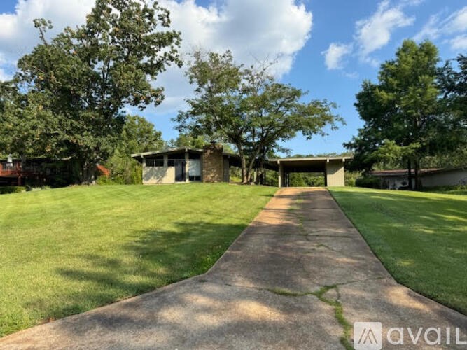 A concrete pathway leads to a building surrounded by greenery.