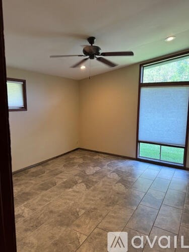 A room with a ceiling fan and a window with blinds.