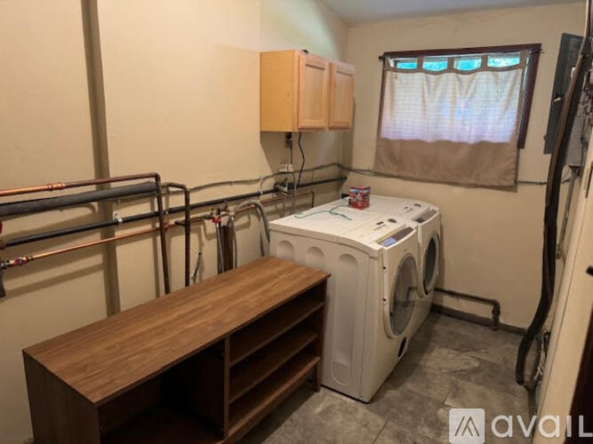 A laundry room with a washer and dryer and a bench.