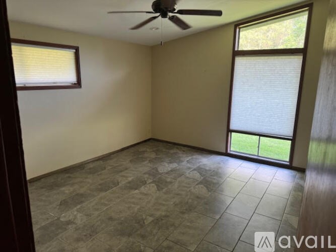 A room with a ceiling fan and sliding glass doors.