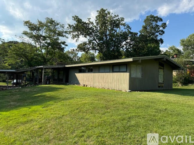A house with a lawn in front and trees in the background.