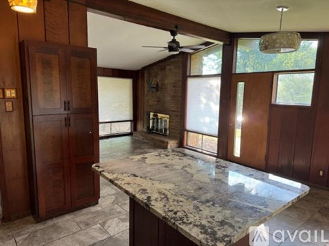 A kitchen with a marble countertop and wooden cabinets.