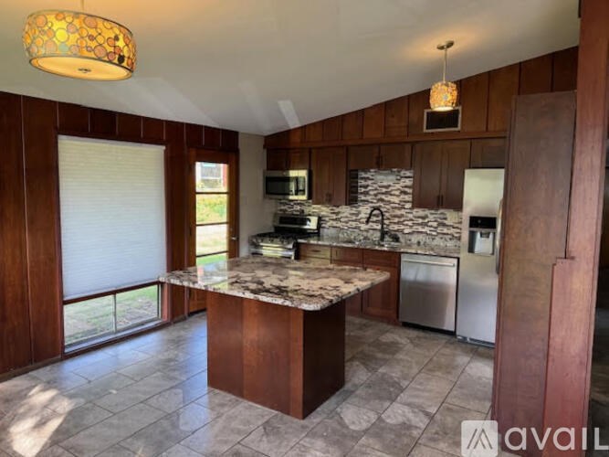 A kitchen with a marble countertop and wooden cabinets.