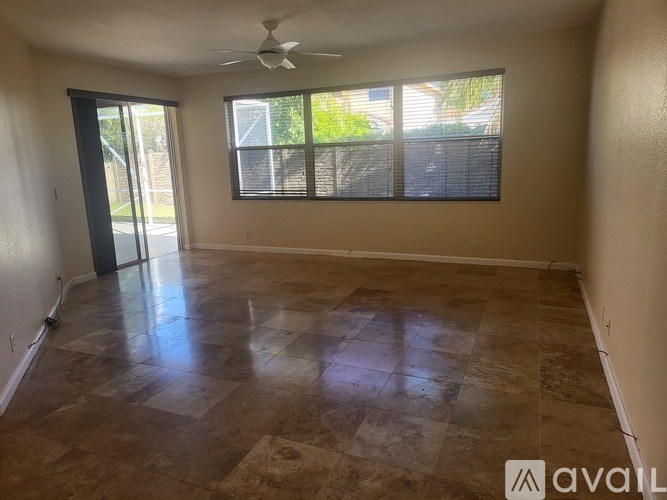 A room with a fan, tiled floor, and sliding glass doors.