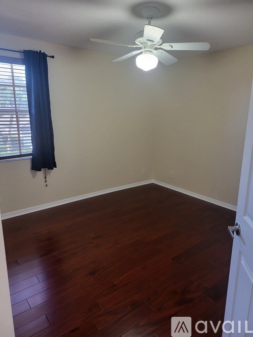 A room with a ceiling fan and wooden flooring.
