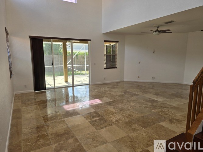 A spacious room with tiled flooring and sliding glass doors leading to a balcony.