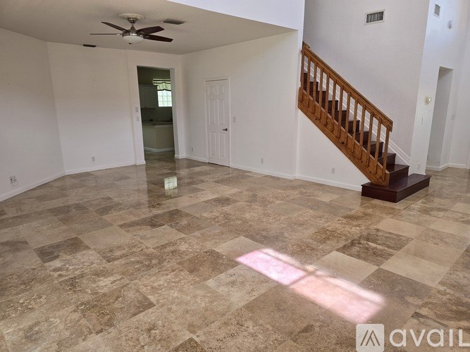 A spacious room with a marble floor and a staircase.