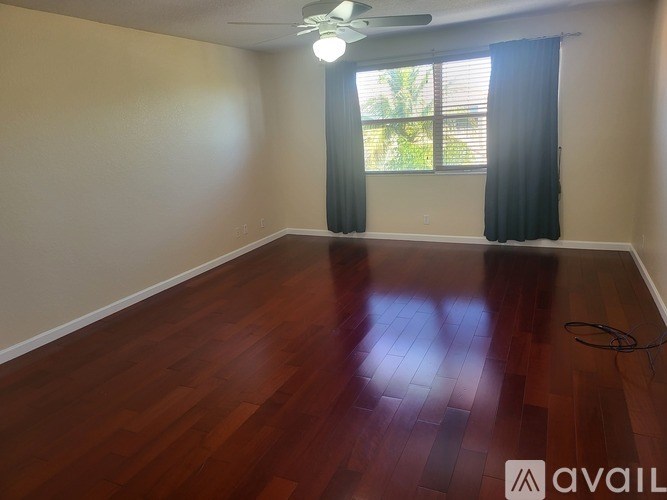 A room with wooden flooring and a window with curtains.