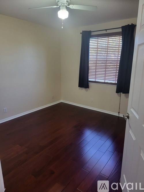 A room with a ceiling fan and a window with black curtains.